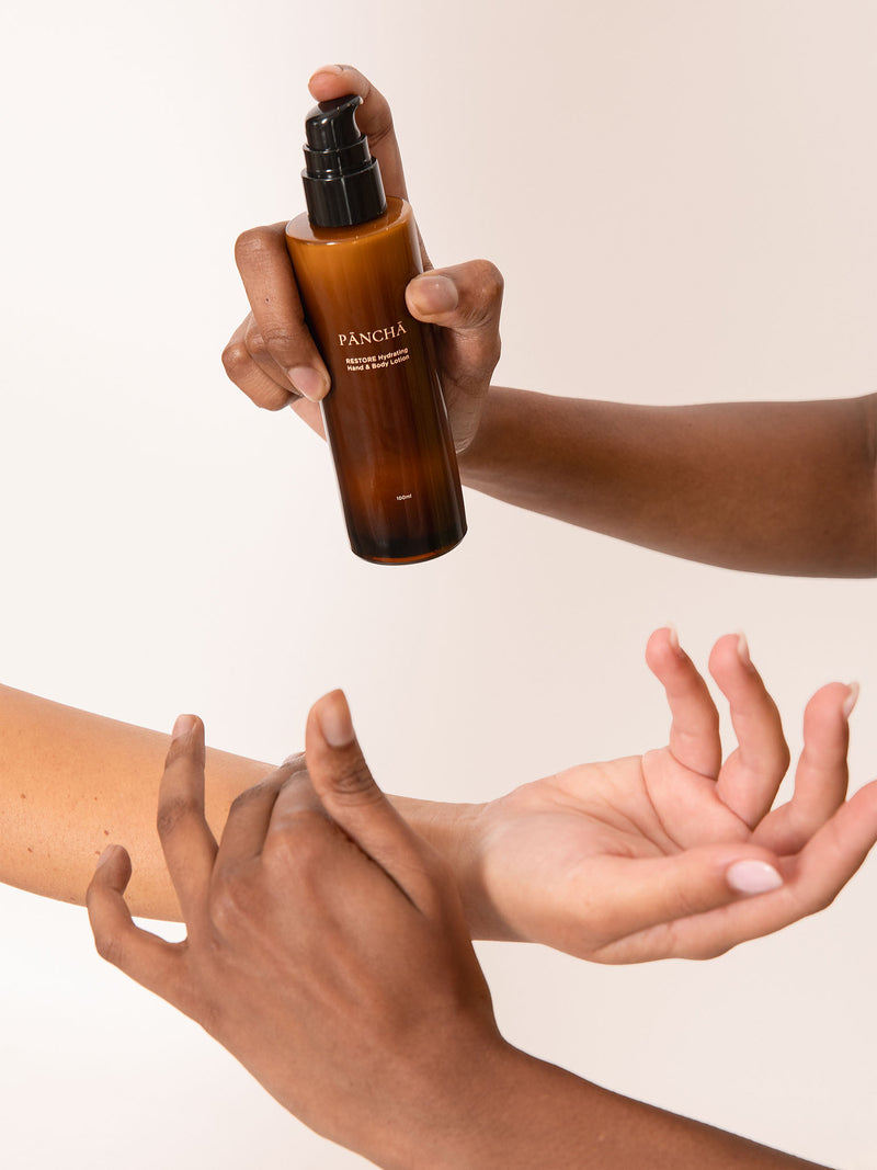 Hands applying Pancha Beauty Restore lotion.