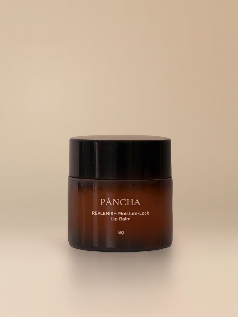 REPLENISH Moisture-Lock Lip Balm in an amber glass jar on a warm studio backdrop