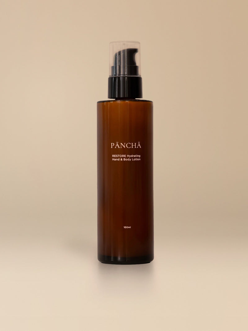 RESTORE Nourishing Hand & Body Lotion in amber glass on a warm studio backdrop